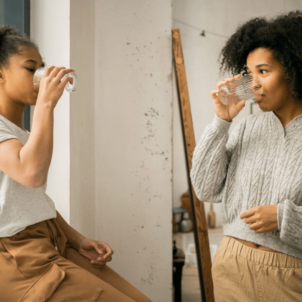 two brown girls drinking water