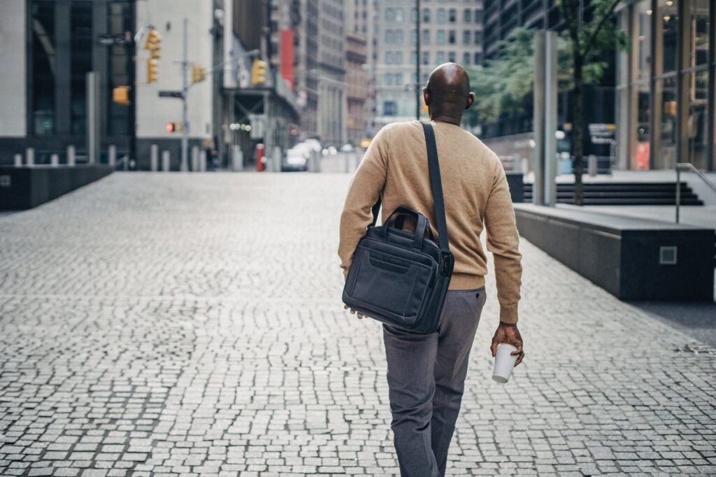 black man walking in hs lunch break on the  street with coffee and bag