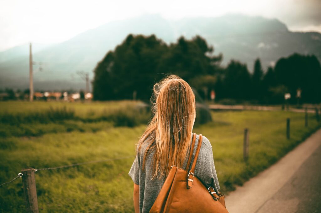 woman carrying brown leather bag and walking to find peace